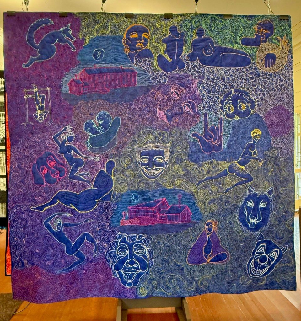 Colorful quilt featuring various playful and abstract designs, including figures, animals, and faces, rendered in intricate stitching on a vibrant purple and blue background.